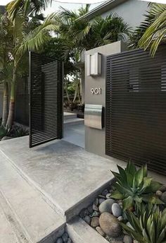 the entrance to a modern home surrounded by palm trees