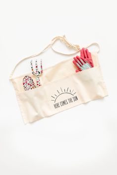 an apron with utensils in it and the words mama printed on it, hanging from a string