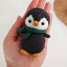 a small crocheted penguin is held in the palm of someone's hand