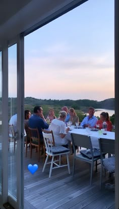 a group of people sitting around a table on top of a wooden deck