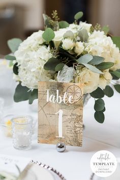 a table with white flowers, greenery and a sign that says table 1 on it