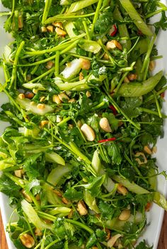 a white platter filled with green vegetables and nuts