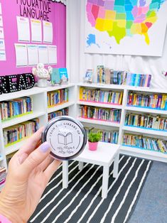 a person is holding up a compass in front of a book shelf filled with books