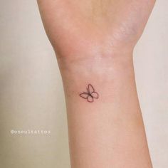 a small tattoo on the wrist of a woman with a butterfly in it's center