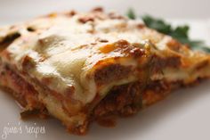 a piece of lasagna on a plate with parmesan cheese and greens