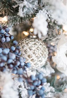 a close up of a christmas tree with snow on it and ornaments hanging from the branches