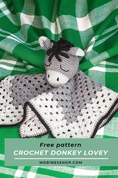 a crocheted donkey is laying on a green blanket