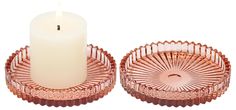 two candles are sitting next to each other in pink glass dishes on a white background