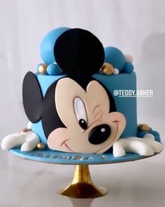 a mickey mouse cake on a blue plate with gold trimmings and black ears