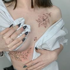 a woman with tattoos on her chest is holding onto a white shirt that has leaves drawn on it