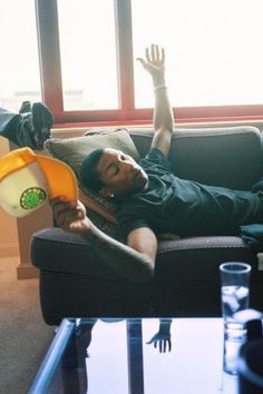 a man laying on top of a couch holding a frisbee in his hand