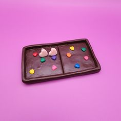 a chocolate tray with hearts and candy on it sitting on a pink surface, ready to be eaten