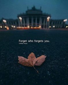 a leaf laying on the ground in front of a building with a quote about forget who forgets you