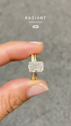 a woman's hand holding a yellow gold ring with two square shaped diamonds on it