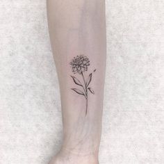 a small flower tattoo on the left ankle is shown in black and grey ink,