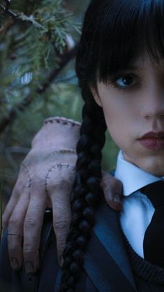 a woman with black hair and braids wearing a white shirt is holding onto her jacket