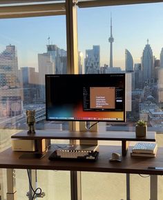 a computer monitor sitting on top of a wooden desk in front of a large window