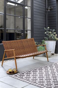 a wooden bench sitting on top of a cement floor next to a potted plant