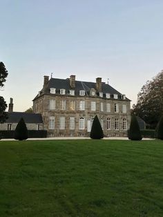 a large building with trees in front of it and grass on the ground around it