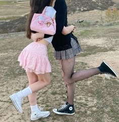 two girls are standing in the grass with backpacks on their backs and one girl is holding a pink bag