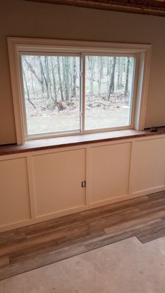 an empty room with two windows in the wall and wood flooring on the ground