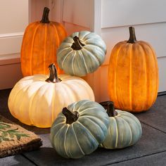 four pumpkins sitting on the ground in front of a house