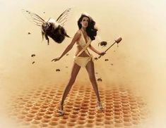 a woman in a bathing suit holding a honey comb and two bees on her back