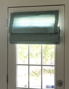 an open window with a green blind on it's valance in front of a white door