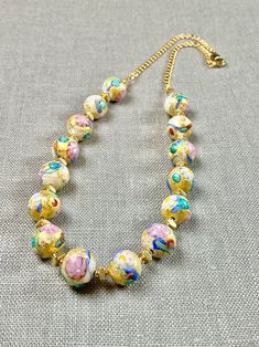 "Murano glass beads with an 'old world' vibe will delight you with genuine 14k gold foil and pastel colors. These artisan created little pieces of art will become one of your favorite jewelry pieces in your wardrobe. The opaque beads are 10mm with flower murrines and subtle textures! Gold fill chain and lobster claw clasp completes the design. The necklace measures 17.5 inches. A wonderful gift for any occasion and arrives in a gift box. ✨ Authentic Murano Glass: Each necklace showcases the unpa Single Strand Murano Glass Necklaces With Round Beads, Murano Glass Large Beads Necklace For Jewelry Making, Murano Glass Beaded Necklaces For Gifts, Multicolor Hand Painted Round Bead Jewelry, Murano Glass Beaded Necklace With Colorful Beads For Gift, Vintage Murano Glass Necklace With Large Beads, Murano Glass Beaded Necklaces With Colorful Beads For Gift, Gift Murano Glass Colorful Beaded Necklaces, Murano Glass Beaded Necklace Gift