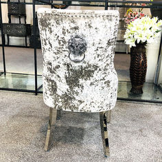 a white and black chair sitting on top of a floor next to a vase with flowers