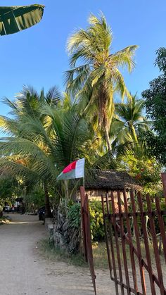 a gate with a flag on it and palm trees in the background