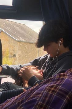 two people sitting in the back seat of a car with headphones hanging from their ears