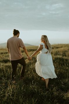 a man and woman holding hands in a field