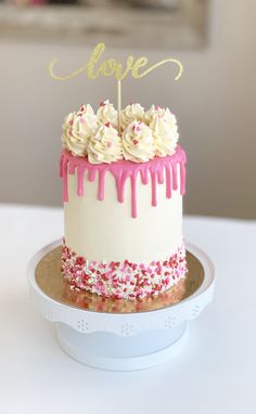 a white cake with pink icing and sprinkles on top that says love