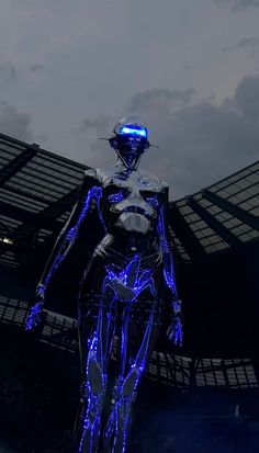 a futuristic man standing in front of a stadium with blue lights on his body and head