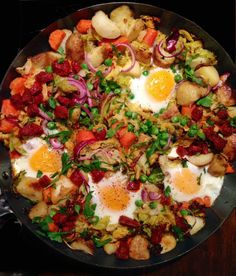 fried eggs and vegetables in a skillet on a table