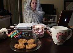 a woman sitting at a desk in front of a laptop computer with cookies on it