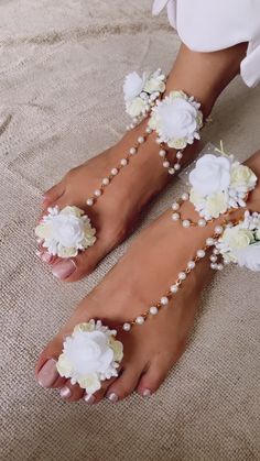 the barefoot bride's feet are adorned with white flowers and pearl beaded bracelets