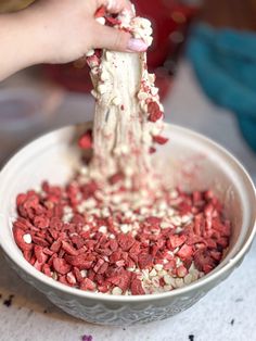 a person scooping something out of a bowl with red and white sprinkles