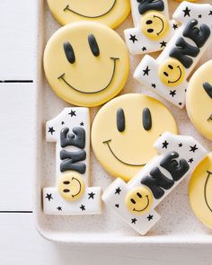 decorated cookies in the shape of smiley faces on a white tray with black and white stars