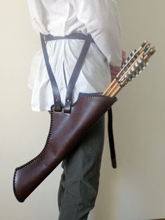 a man is holding a bag with arrows in it and wearing suspenders on his pants