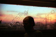 a man sitting in front of a window at sunset