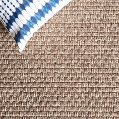 a blue and white pillow sitting on top of a woven material covered flooring area