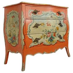 an orange painted chest with flowers and birds on the front, sitting against a white background