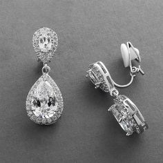 two pairs of diamond earrings on a gray surface with clippings to the side