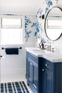 a blue and white bathroom with floral wallpaper on the walls, two sinks and a mirror