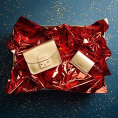 a red and gold bag sitting on top of a piece of tin foil covered in confetti