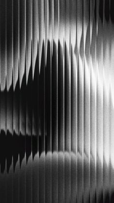 an abstract black and white photo of wavy lines on a wall with the light coming through it