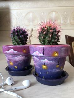 two potted plants sitting next to each other on top of a wooden table with headphones