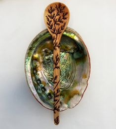 two wooden spoons sitting on top of an abana shell with leaves painted on it